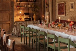 The tables in Da Costa with lit candles and flowers on them set up for a group.