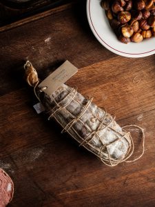 Westcombe Coppa dried meat on a plate with chestnuts in the background.