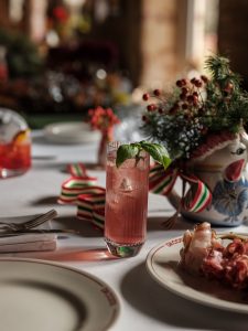 Festive spiced fig cocktail in a high ball glass on a table with seasonal greenery in the background.