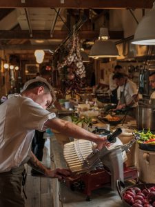 Charcuterie being sliced in a busy restaurant kitchen.