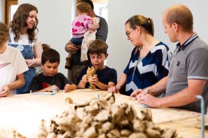 Three children completing a craft activity with three adults watching.