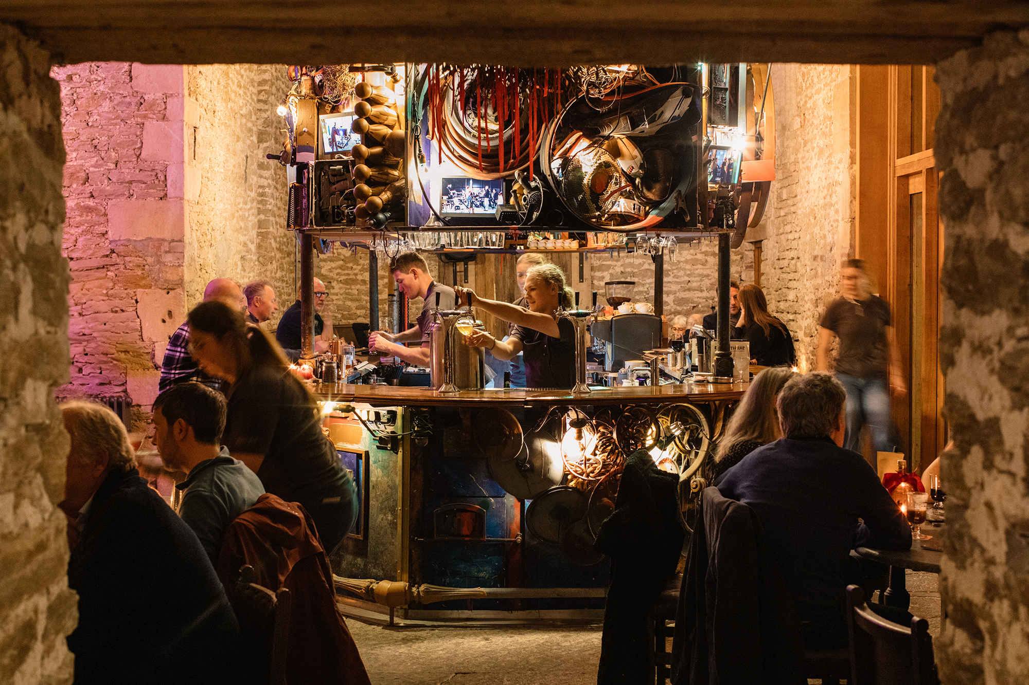 People sitting around the site-specific Roth Bar as a person pours beer behind the bar.