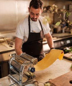 Pasta being rolled through a pasta machine.