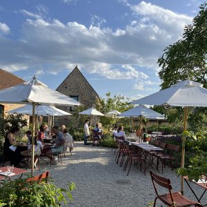 People sitting at tables under umbrellas in the early evening.
