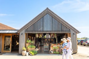 People walking past a store with large doors open to show the produce.