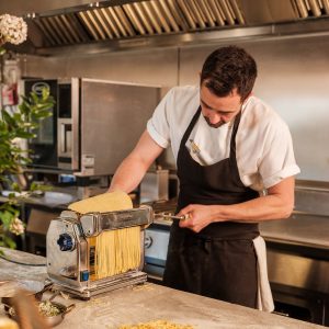 A person creating pasta through a machine.