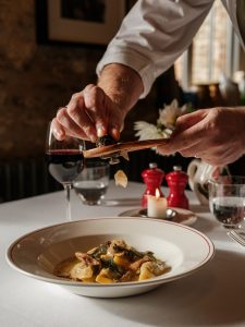 A chef shaving truffle onto a bowl of pasta