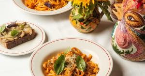 Bowls of pasta on a white table cloth and a chicken shaped vase