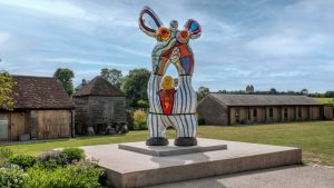A statue of a being with arms in the air on a plinth.