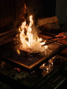 A piece of meat being cooked on a grill over fire