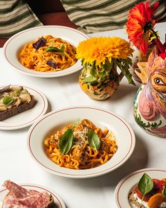 Bowls of pasta on a white table cloth and a chicken shaped vase